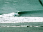 Una ola vista desde lejos, con personas practicando surf
